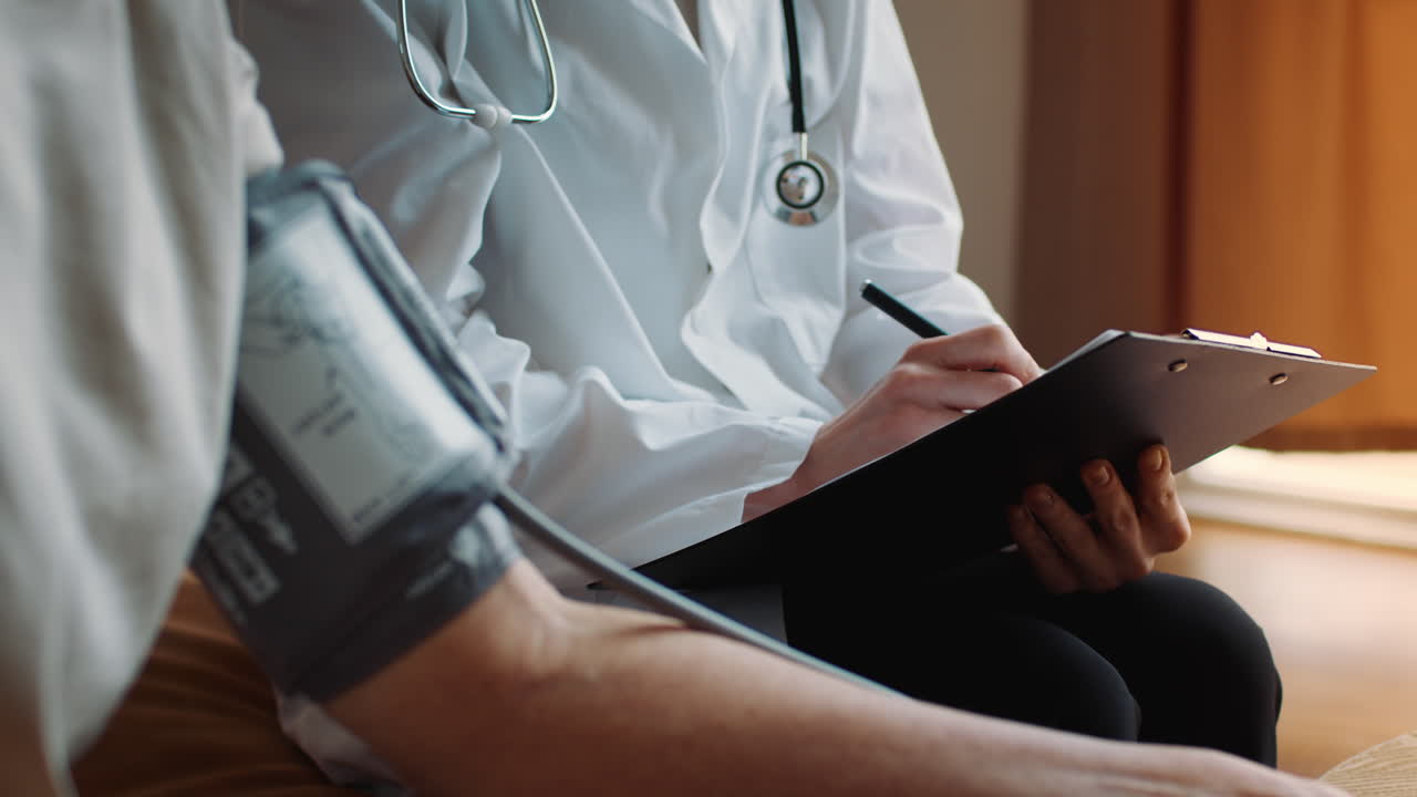 Doctor taking blood pressure and writing notes