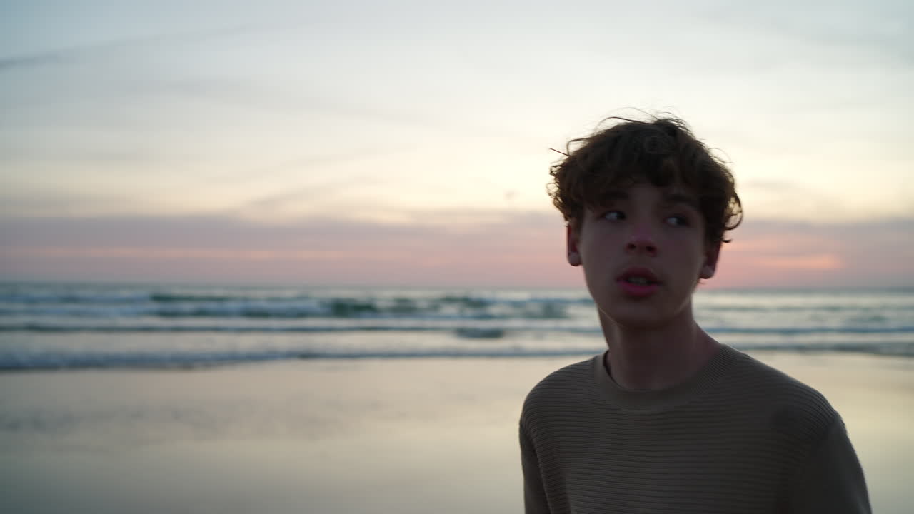 Teenager standing near ocean shoreline, breathing deeply while gazing at golden sunset horizon, experiencing serene moment of peaceful reflection and natural tranquility