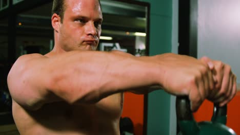 muscular man lifting kettle bell