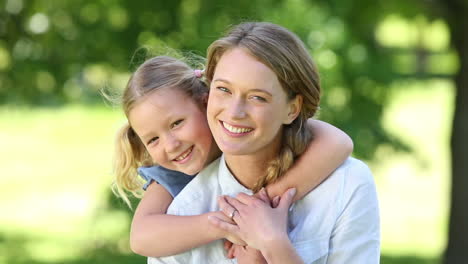 happy little girl hugging mother in the park