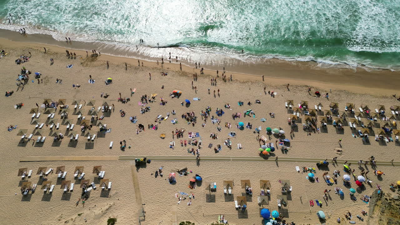 Aerial overview of people enjoying a warm day at the Guincho beach, in Portugal