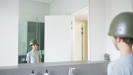 boy in military helmet looking in bathroom mirror