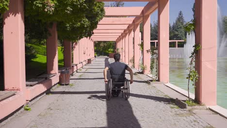 disabled young man is walking down the street in his wheelchair.