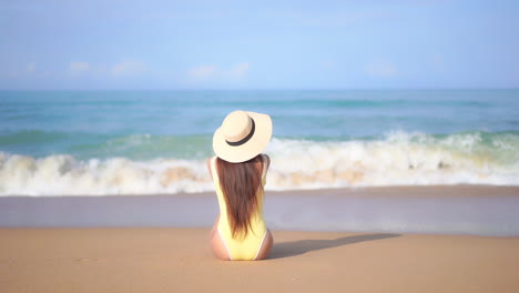 Espalda-De-Una-Mujer-Solitaria-En-Traje-De-Baño-Sentada-En-La-Arena-De-Una-Playa-Tropical-Frente-A-Las-Olas-Del-Mar-Y-El-Horizonte-Azul