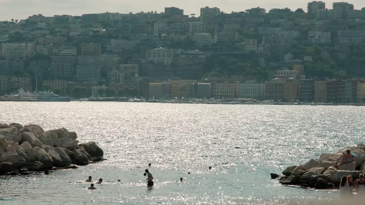 NAPOLI, ITALIA - 2 MAGGIO 2022: una bellissima vista del mare davanti al quartiere Chiaia, con persone che nuotano