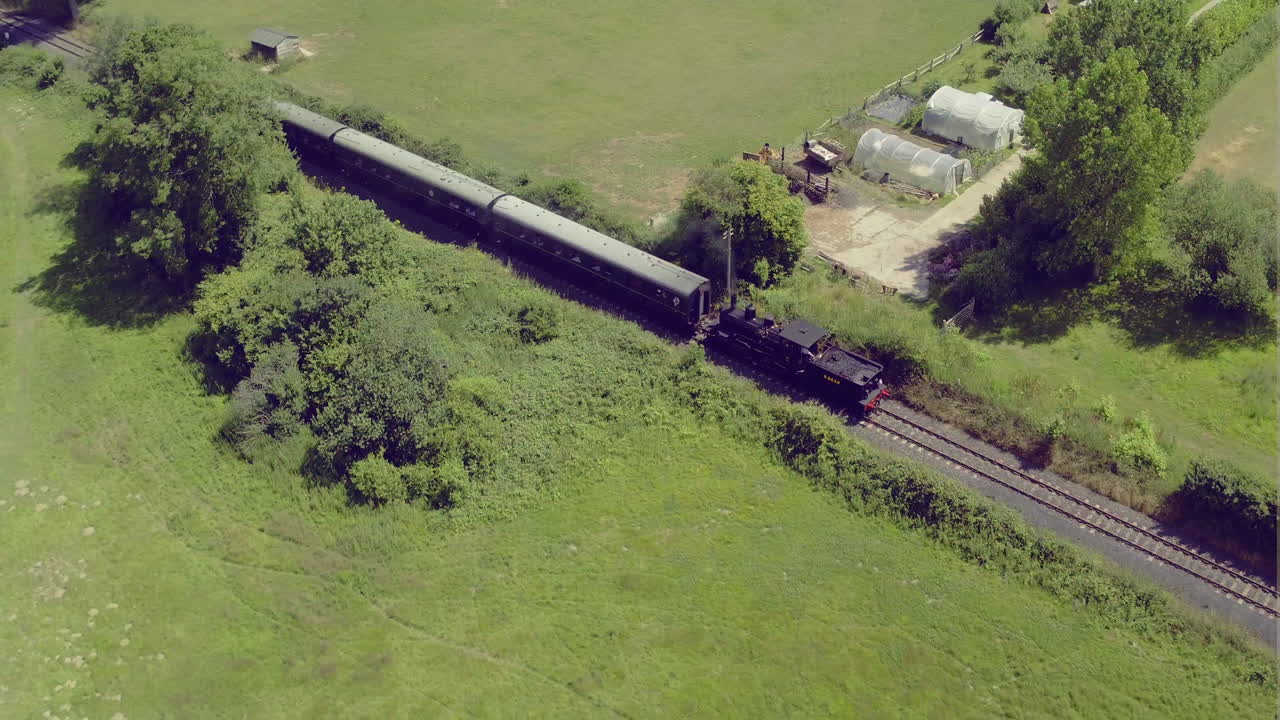 객차가 있는 증기 기관차를 추적하는 공중 풀백 샷