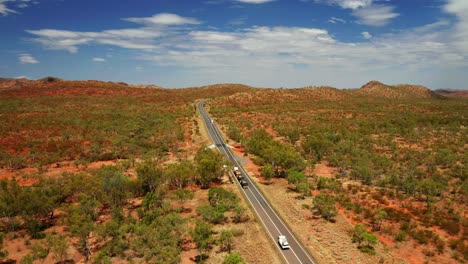 Trucks-And-Vehicle-Driving-Across-Highway-Passing-Through-Bushland-In-Outback,-Northern-Territory,-Australia