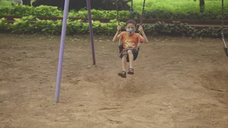 beautiful male child sitting on swing in forest park enjoy summer