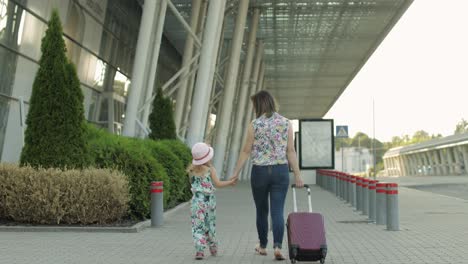 Mother-and-daughter-walking-to-airport.-Woman-carrying-suitcase-bag.-Child-and-mom-vacation.-Rear