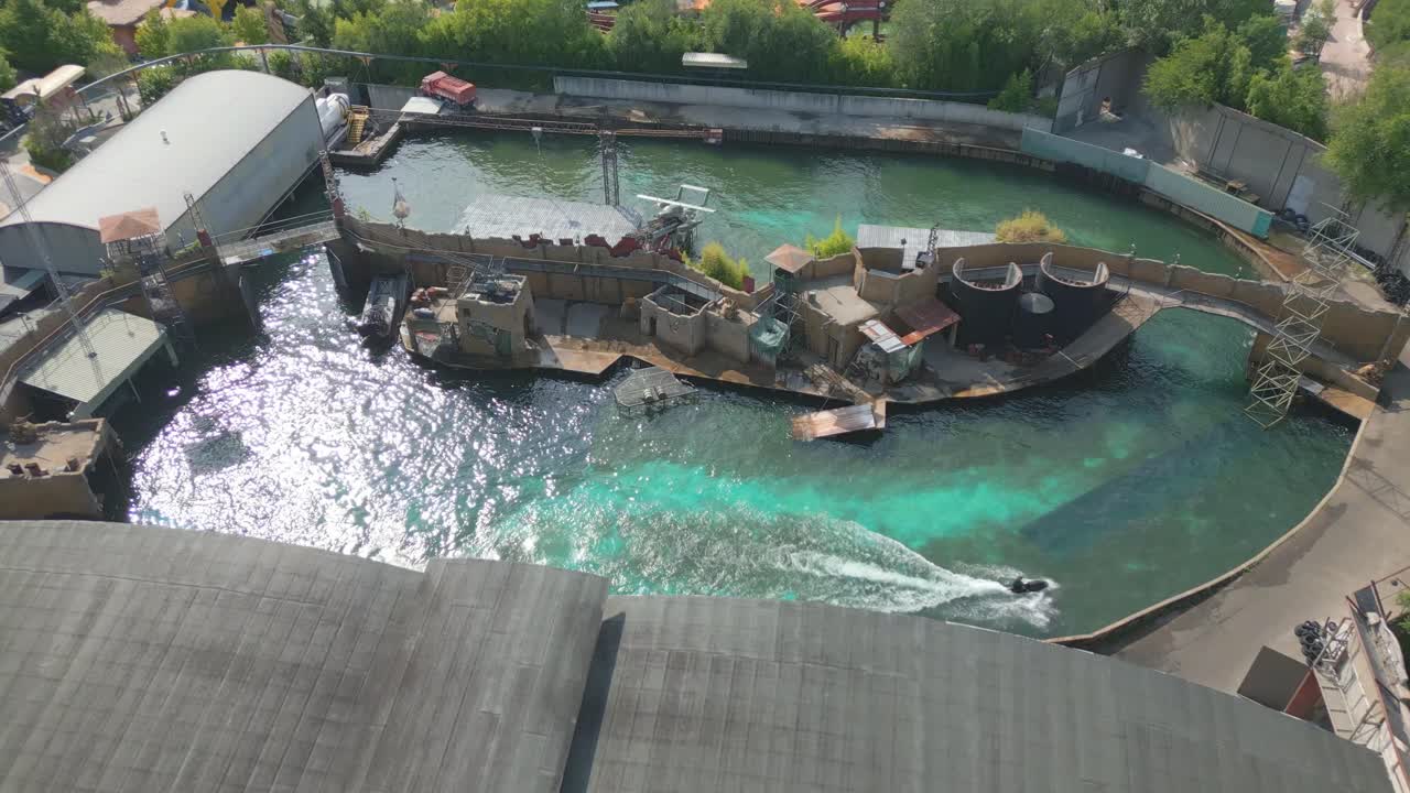 드론이 큰 파도 수영장 위로 올라와 이탈리아 가르다 호수 근처의 놀이 공원에서 즐거움을 위해 제트 스키를 돌고 있습니다.