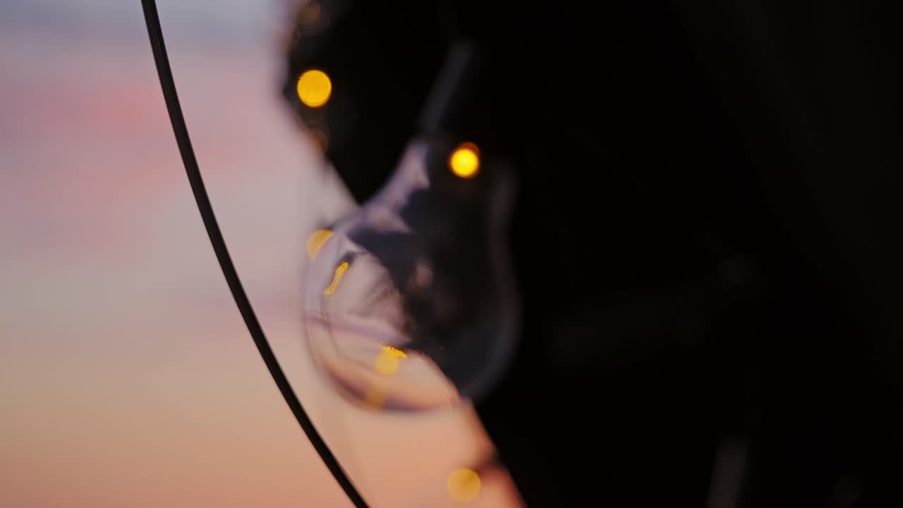 Transizione cinematografica da una lampadina in primo piano a lucine scintillanti all'ora d'oro.