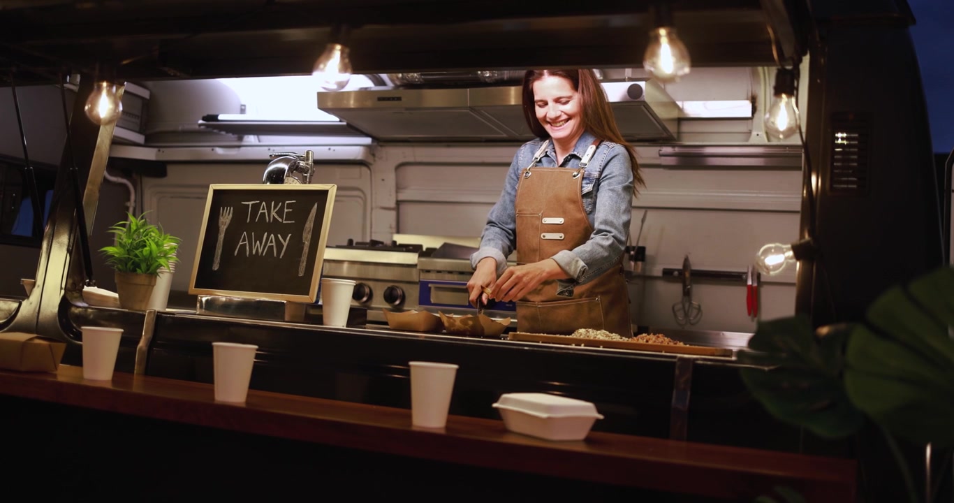 Donna felice che prepara e serve cibo in un food truck di notte