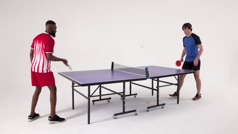 competing in table tennis, two men playing intensely in studio setting