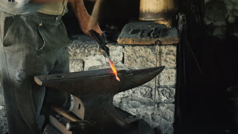 traditional crafts - a blacksmith forges an ironwork only a hammer and anvil are visible in the fram