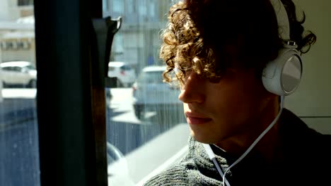 viajero masculino escuchando música en auriculares mientras viaja en el autobús 4k