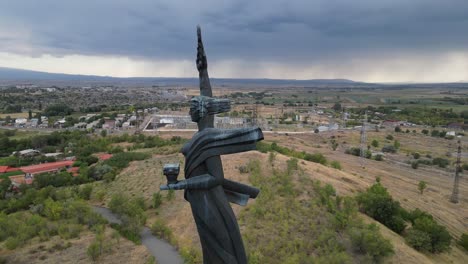 aerial orbits mother armenia statue in gyumri under dark heavy cloud