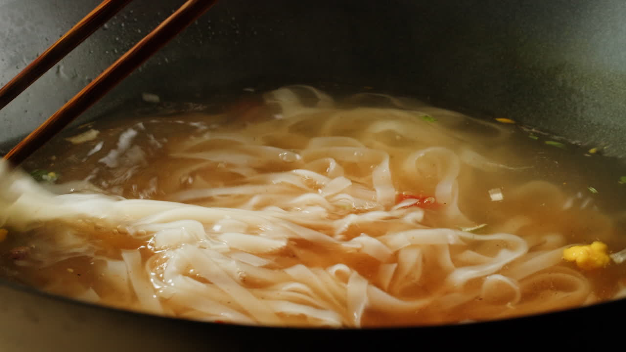 Cooking Rice Noodles in a Pot with Chopsticks