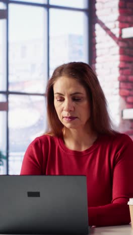 vertical video casual focused woman sitting at her desk and reading research papers