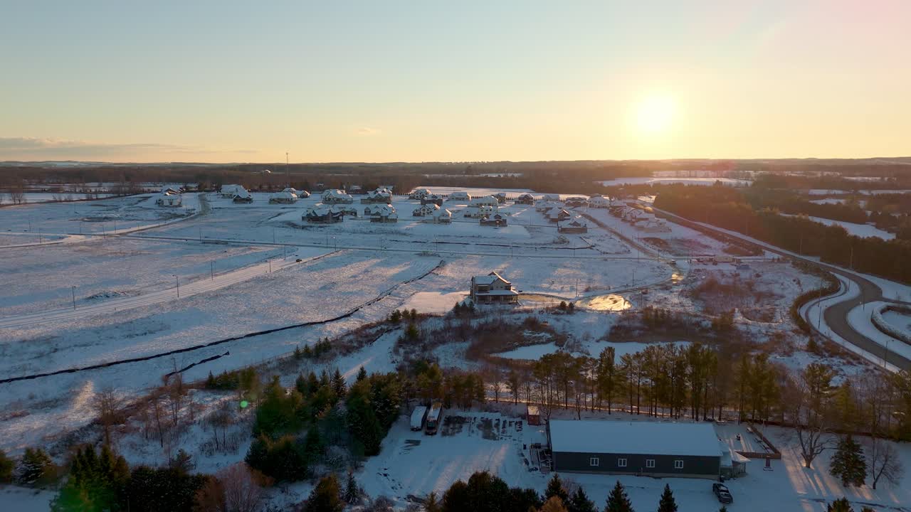 Winter aerial of a new housing development in Alton, Caledon, Ontario, captured at sunrise with snow-covered lots, growing residential blocks, and surrounding rural landscape