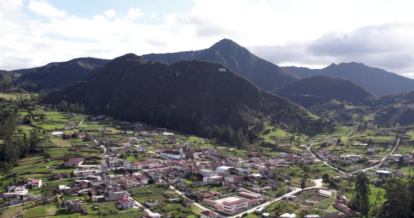 Video cinematografico aereo con drone sulla bellissima città tradizionale di Jima in Ecuador, che rivela le splendide case rurali e le vaste montagne sullo sfondo, durante un pacifico pomeriggio di sole