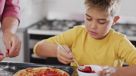 Happy-caucasian-grandfather-and-grandson-making-pizza-in-kitchen,-slow-motion