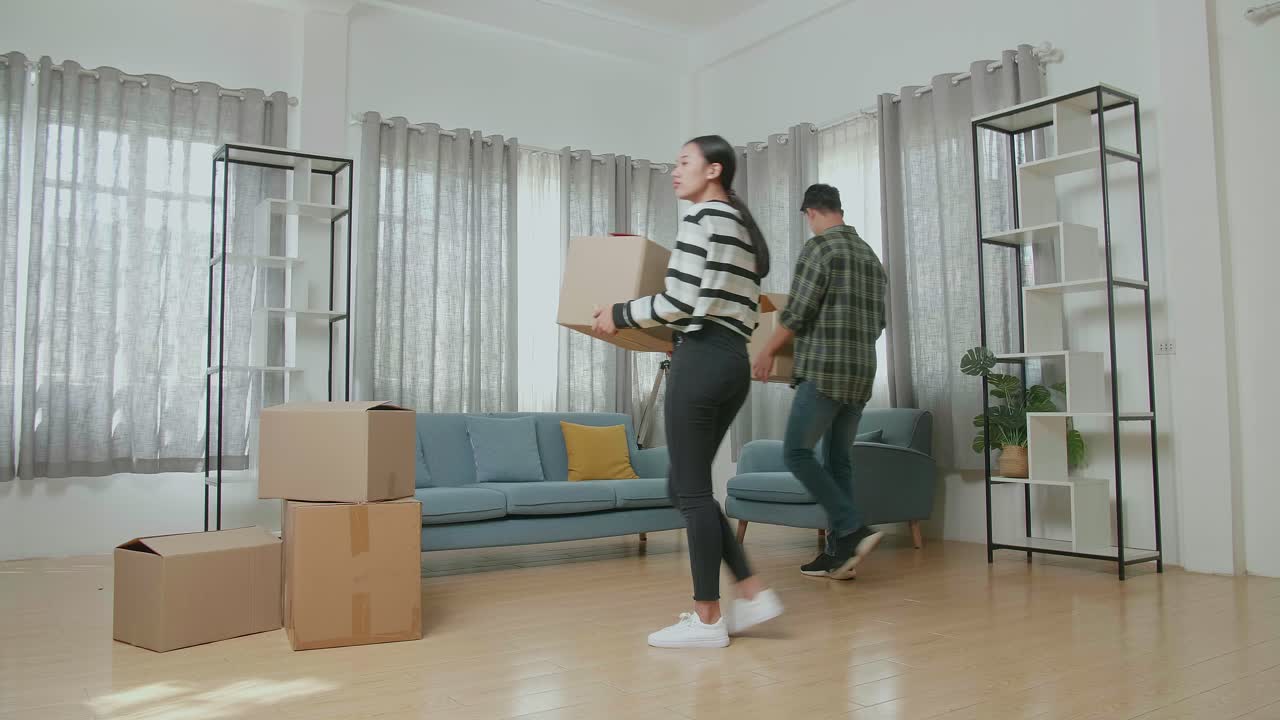 una joven pareja asiática feliz celebrando el final de llevar cajas de cartón con cosas a una nueva casa. se mudan a una nueva casa juntos