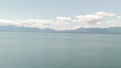 Standing-on-the-cliff-edge-of-the-Helliwell-meadow-gazing-at-the-Rocky-Mountains-in-the-background-just-beyond-the-ocean-waters-on-Hornby-Island-in-British-Columbia,-Canada