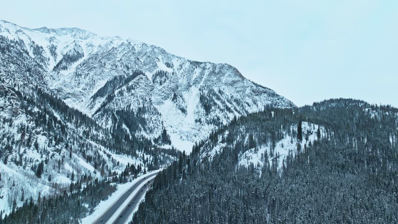 Aerial tracking right of a highway weaving through snow covered forests and mountains near Frisco and Silverthorne