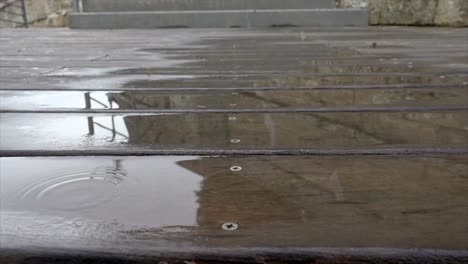 gotas de lluvia vertiendo y rebotando en una terraza de madera