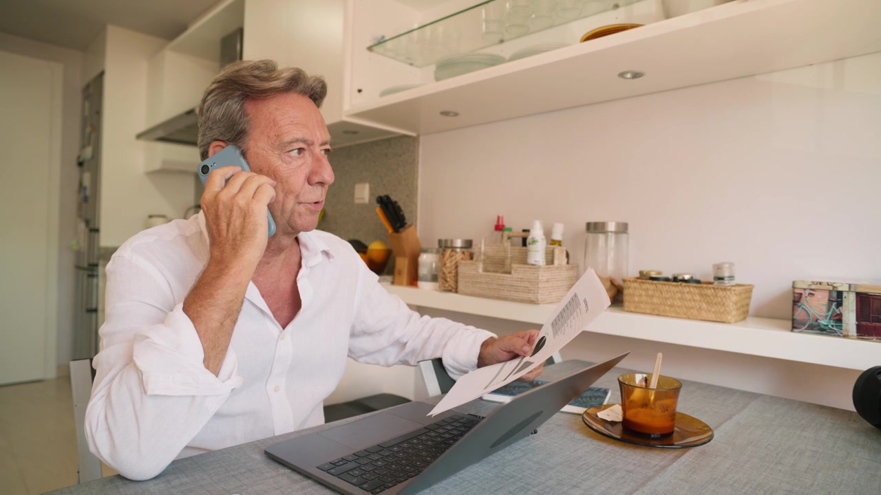 Uomo maturo che lavora da casa e parla al telefono