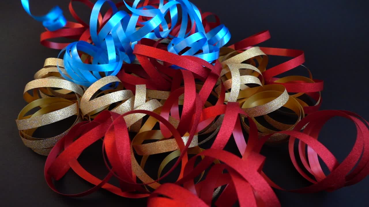 Rubans de fête multicolores rouges, dorés et bleus sur fond sombre