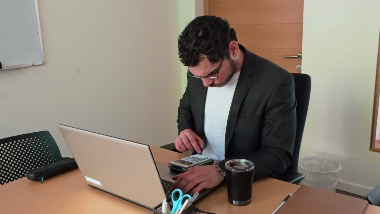 Analyst Using Calculator and Laptop for Data
