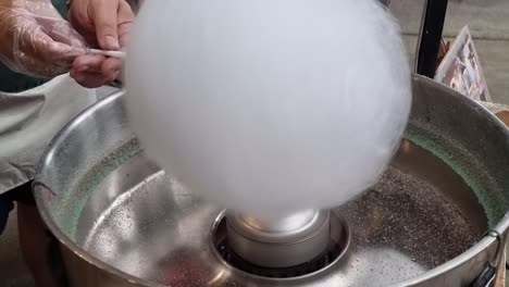 la mano del hombre girando máquina eléctrica de algodón de caramelo