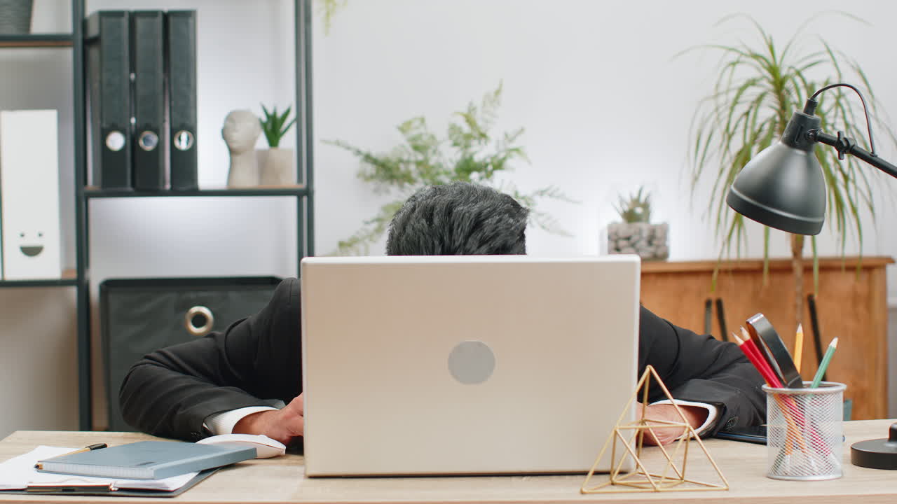 Office businessman hiding behind laptop computer making funny silly face fooling around disrespect