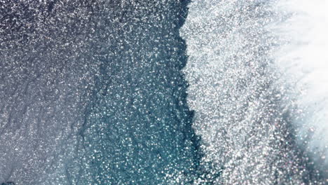 a serene aerial view of glittering sunlight reflecting off a rippling ocean surface