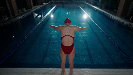 woman in a red swimsuit standing at the edge of a swimming pool