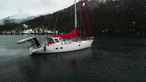 Aerial-view-orbiting-a-sailboat-parked-between-snowy-mountains-of-Alaska