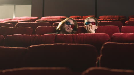 vista lejana de una pareja con anteojos 3d sentados en el cine mientras ven una película y comen palomitas de maíz