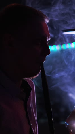 man smoking hookah in a night club