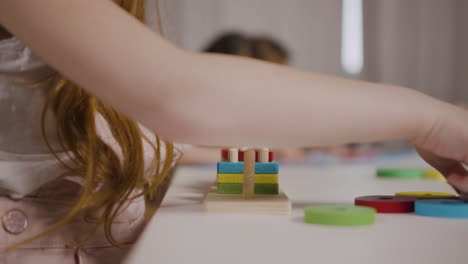 Close-Up-Of-An-Unrecognizable-Ginger-Little-Girl-In-A-Montessori-School-Playing-With-Shapes-Stacking