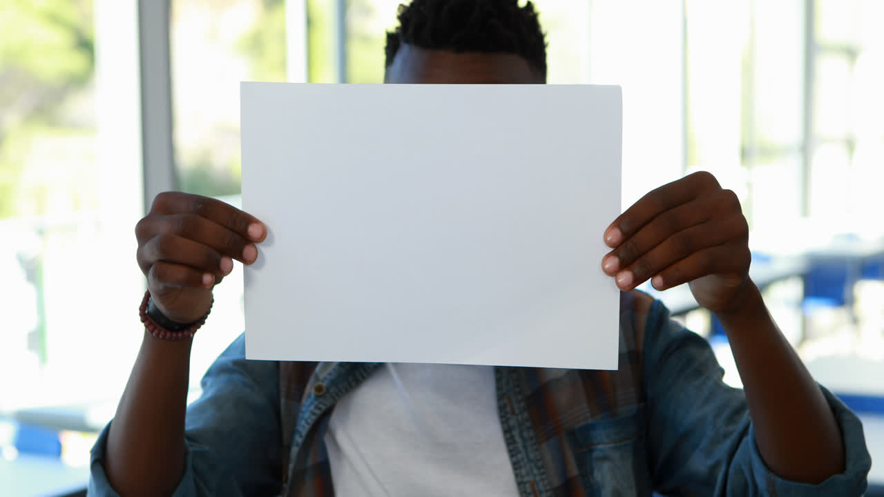 Schoolboy holding blank placard in classroom