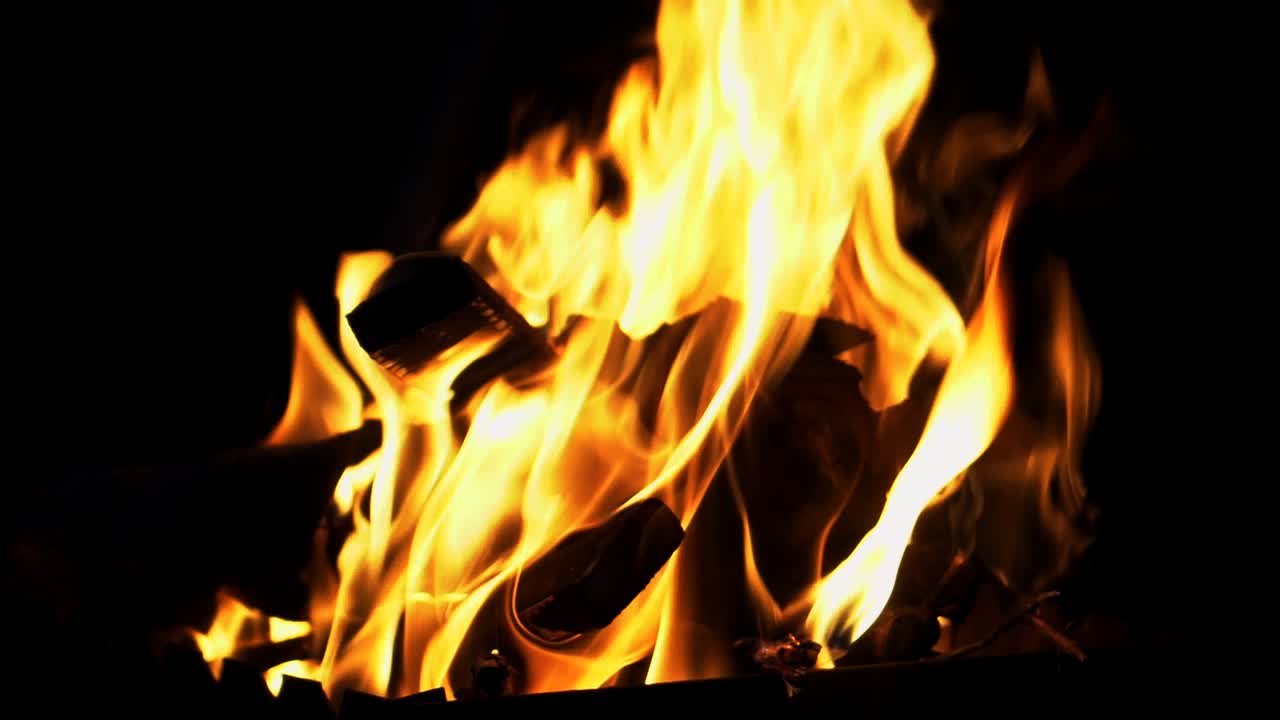 Ceppi fumanti bruciavano in un fuoco vivido di notte. Sfondo suggestivo con fiamma arancione di un falò. Immagine incredibilmente dettagliata di un falò dall'interno