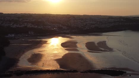 Golden-heavenly-sunset-rays-aerial-view-reflected-over-romantic-exotic-beach-coastline-high-angle-right-dolly