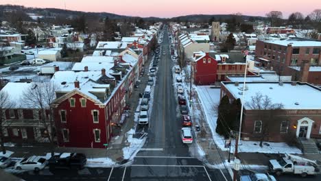 aerial straight flight over traffic on snowy main street of small town in america