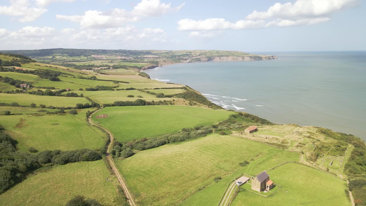 tomada aérea de drones de la costa de north yorkshire cerca de ravenscar con campos verdes y océano