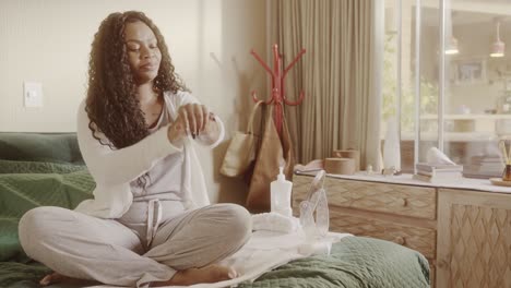 woman applying lotion as part of her personal care routine in a cozy bedroom
