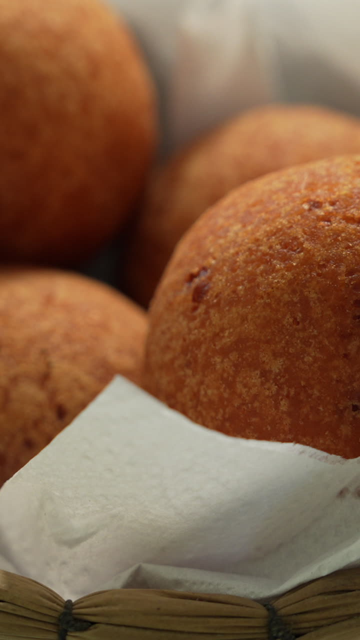 Delicious Colombian buñuelos in a close-up vertical video. Golden brown, crispy texture in soft lighting, showing the rich details of this traditional fried snack