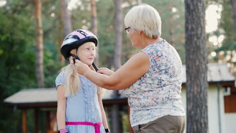 Senior-Woman-Puts-On-A-Protective-Helmet-For-Her-Daughter-Concept---Care-And-Safety-4k-Video