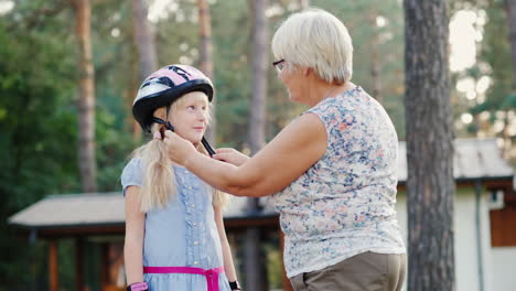 senior woman puts on a protective helmet for her daughter concept - care and safety 4k video