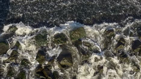 Agua-Que-Fluye-Rápidamente-Sobre-Rocas-En-Un-Río-De-Arriba-Hacia-Abajo